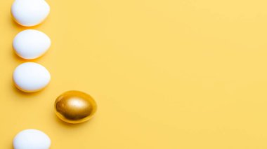 Paskalya çerçevesi. Mutlu Paskalya dekorasyonunda pastel sarısı arka planda altın, beyaz renkli yumurta. Düzlükte şenlik tasarımı