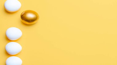 Paskalya tatili. Mutlu Paskalya dekorasyonunda pastel sarısı arka planda altın, beyaz renkli yumurta. Fotokopi alanı olan bahar tatili üst görünümü