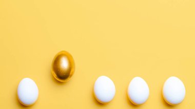 Paskalya seti. Mutlu Paskalya dekorasyonunda pastel sarısı arka planda altın, beyaz renkli yumurta. Kopyalama alanı olan geleneksel tasarım