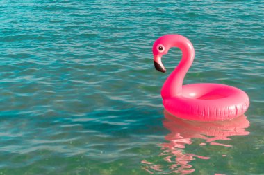 Deniz arka planı. Mavi okyanus suyunda pembe şişirilebilir flamingo. Deniz yazı plajı arka planı için. Lüks yaşam tarzı seyahati