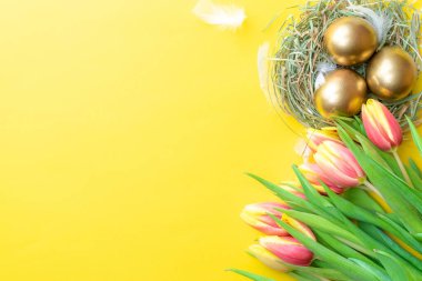Paskalya yumurtaları altın. Bahar laleli altın rengi yumurta, Mutlu Paskalya dekorasyonunda pastel sarısı arka planda beyaz tüyler. Kutlama paskalya tasarımı. Düz yatış, üst görünüm