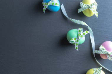 Paskalya çerçevesi. Mutlu Paskalya dekorasyonunda koyu kaba taştan arka planda bant şeritli renkli yumurta. Düzlükte şenlik tasarımı