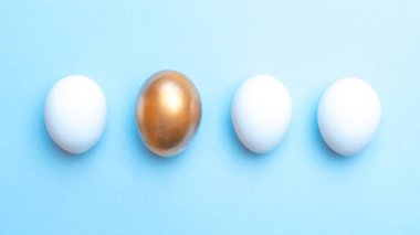 Paskalya arka planı mavi. Mutlu Paskalya dekorasyonunda pastel mavi arka planda altın, beyaz renkli yumurta. Düz yatış, üst görünüm