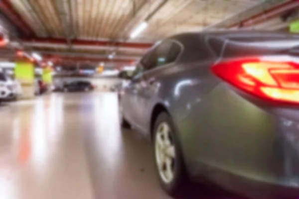 Parking lot cars blurred. Car lot parking space in underground city garage. Empty road asphalt background in soft focus. Industrial Shed or Parking Lot