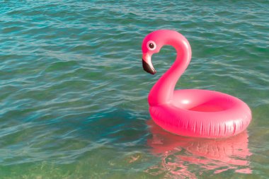 Yaz zamanı. Mavi okyanus suyunda pembe şişirilebilir flamingo. Deniz yazı plajı arka planı için. Çocuklar için komik bir oyuncak.
