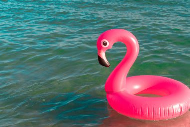 Yaz eğlencesi plajı. Yazın okyanus kıyısında mavi deniz suyunda şişme pembe flamingo. Çocuklar için komik bir oyuncak.
