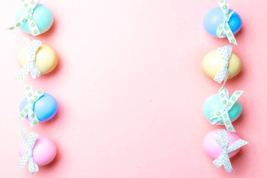 Paskalya yumurtası avı. Mutlu Paskalya dekorasyonunda pastel pembe arka planda bant şeritli renkli yumurta. Üst görünümde geleneksel tasarım