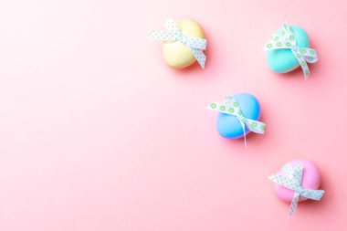 Paskalya arka planı pembe. Mutlu Paskalya dekorasyonunda pastel pembe arka planda bant şeritli renkli yumurta. Düz yatış, üst görünüm