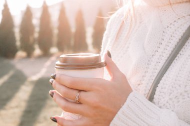 Cafe elleri doğaldır. Fincanlı mutlu genç kız sabah güneşinde çay içer. Güzel kadın yaşam tarzı