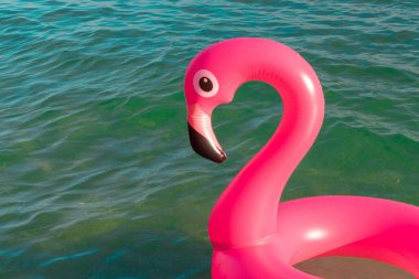 Yaz zamanı. Mavi okyanus suyunda pembe şişirilebilir flamingo. Deniz yazı plajı arka planı için. Çocuklar için komik bir oyuncak.