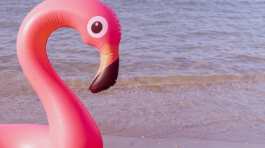Yaz eğlencesi plajı. Yazın okyanus kıyısında mavi deniz suyunda şişme pembe flamingo. Çocuklar için komik bir oyuncak.