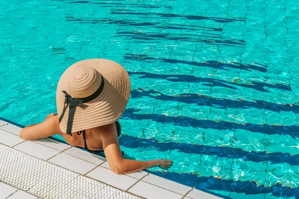 Pool party girl. Young sexy woman in straw hat, bikini swimsuit, sunglasses swimming in blue pool water. Resort spa in hotel on travel holidays vacation