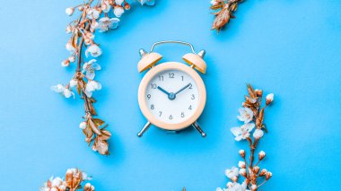 Sakura çiçekleri ve çiçeklerle süslenmiş çalar saat mavinin üzerinde. Sancak olarak, arka planda çiçek açan kiraz dalları. Rüya gibi romantik bir görüntü, manzara manzarası, kopyalama alanı