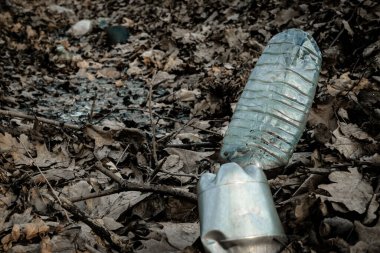 Çevre kirliliği. Ormanda çöp atmak. Ormandaki plastik çöpler. Kullanılan kirli plastik şişelerin ekolojik sorunu