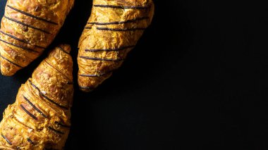 Kruvasan dokusu. Fransız kahvaltısı kruvasanları, fırında çikolatalı taze hamur ekmeği ve koyu taşlı arka plan. Ekmek fırını ürünleri kafe konsepti, düz konum.