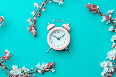 Mayıs çiçekleri. Bahar çiçekleri ve çiçekli Nisan çiçekleri mavi arka planda çalar saat. Çiçek açan ağaçla güzel bir sahne. Paskalya güneşli bir gün. Meyve bahçesi arkaplanı bulanık. İlkbahar