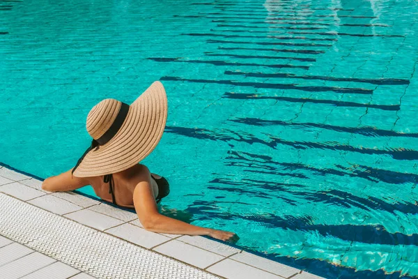 夏のコンセプトの背景 青いプールの水でビキニ水着 サングラス 麦藁帽子の幸せな若いセクシーな女の子 休暇中のホテルのリゾートスパ — ストック写真