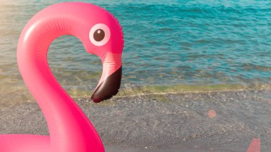 Tropikal arka plan. Mavi okyanus suyunda pembe şişirilebilir flamingo. Deniz yazı plajı arka planı için. Asgari yaz konsepti
