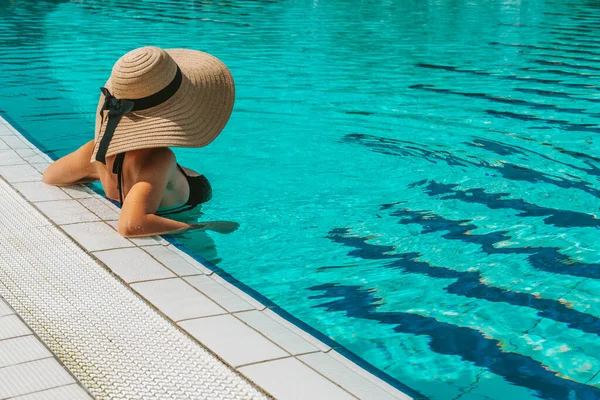 夏の帽子プール 藁帽子の若いセクシーな女性 ビキニ水着 青い水で泳ぐサングラス ラグジュアリーライフスタイル旅行 — ストック写真