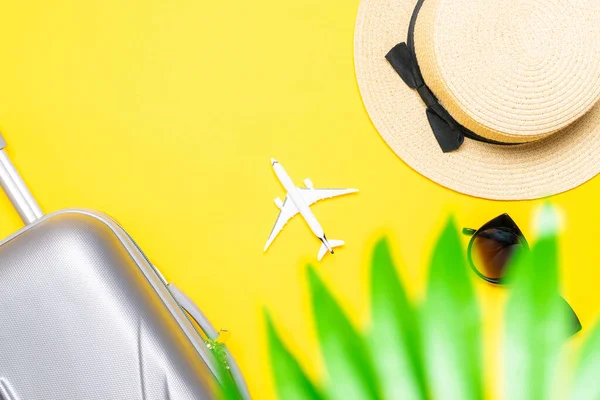 Sea background. Travel accessories with suitcase, white plane, palm leaves in minimal trip vacation concept on yellow background. Tranquil beach scene with copy space