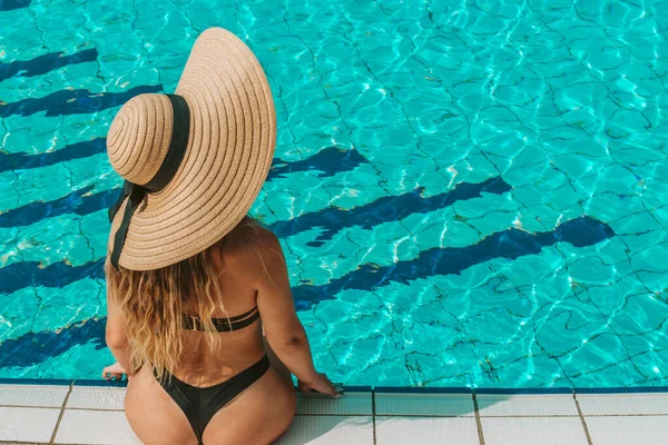 女の子の旅行 サンハットの若いセクシーな女性 ビキニ水着 サングラスは青いプールの水で泳ぐ 帽子を頭に被せなさい リゾート 休暇で — ストック写真