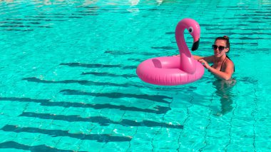 Yaz eğlencesi. Yaz mevsimi için havuz suyunda Pembe şişme flamingoyla yüzen bir kız. Lüks yaşam tarzı seyahati