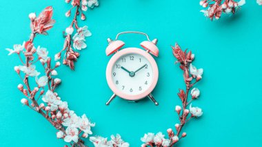 Mayıs çiçekleri. Bahar çiçekleri ve çiçekli Nisan çiçekleri mavi arka planda çalar saat. Çiçek açan ağaçla güzel bir sahne. Paskalya güneşli bir gün. Meyve bahçesi arkaplanı bulanık. İlkbahar