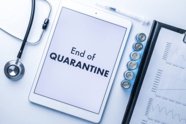 Karantina sona erdi. İğneli şırınga, hastane sağlık raporları, doktor steteskobu ve tıbbi ekipman geçmişi için yazılı beyaz tablet. Karantina kavramının sonu