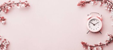 Bahar zamanı geçmişi. Mayıs çiçekleri ve Nisan çiçekleri ve pembe alarmlı saat. Yumuşak odaklı, çiçek açan kayısı makrosu dalları. Kopya alanı olan Paskalya tebrik kartları için. İlkbahar
