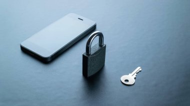 İnternet koruması. Modern uzay gri cep telefonu, asma kilit, anahtar arka planda. Darkweb, darknet ve hack konsepti