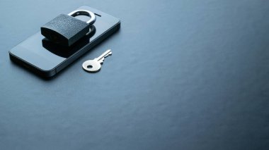 Teknoloji güvenliği. Modern uzay gri cep telefonu, asma kilit, anahtar arka planda. Akıllı telefon güvenlik ihlali kavramı