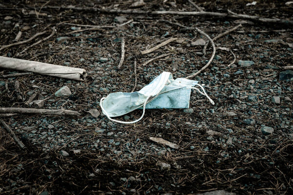 Pollution garbage, medical mask in environment forest. Rubbish plastic waste on woodland. Empty used dirty bottles in the concept of nature conservation from pollution.
