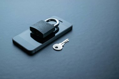 İş güvenliği koruması. Modern uzay gri cep telefonu, asma kilit, anahtar arka planda. Akıllı telefon dolandırıcılığı, online dolandırıcılık ve siber güvenlik tehdidi