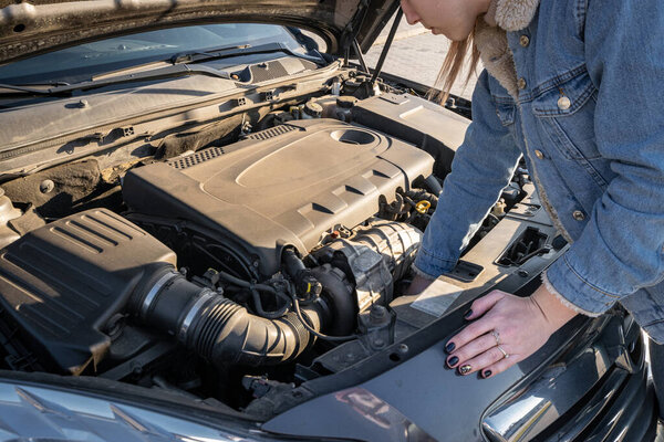 Машина сломалась. Девушка-водитель возле открытого капота авто. Концепция транспортного средства