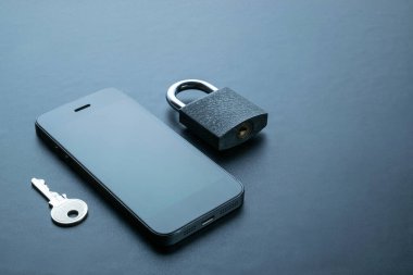 Gezici güvenlik. Modern uzay gri cep telefonu, asma kilit, anahtar arka planda. Kimlik hırsızlığı ve siber güvenlik kavramı