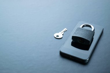 İnternet koruması. Modern uzay gri cep telefonu, asma kilit, anahtar arka planda. Darkweb, darknet ve hack konsepti.