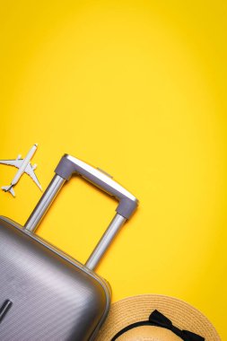 Plaj geçmişi. Kadın aksesuar gezgini: bavul, beyaz uçak, sarı arka planda güneş gözlüğü ve mesaj için boş alan. Yaz tatili konsepti tasarımı.