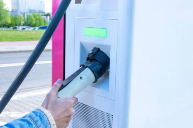 Elektrikli araba şarjı. Gelecekteki şarj istasyonunda eko yeşil enerji hibrit aracına güç kablosu tak. Yakıt teknolojisini elektrik bataryasıyla şarj et. Çevre dostu sürdürülebilir enerji kavramı