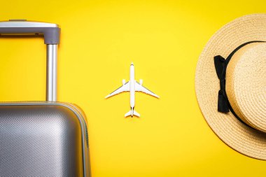 Yaz konsepti geçmişi. Çantalı seyahat aksesuarları, beyaz bir uçak, sarı arka planda minimum tatil konsepti olan palmiye yaprakları. Kopyalama alanı, yaz tatili ve iş seyahati kavramı