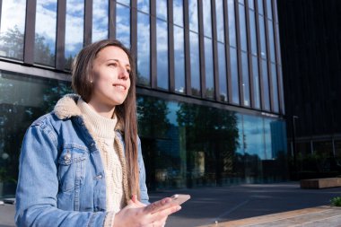 Podcast arka planı. Mobil akıllı telefon ekranlı, podcast uygulamalı, sesli kulaklıklı mutlu genç seksi kız. Ses telsiz cihazları kadının elinde. Kayıt stüdyosu arka planı