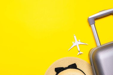 Plaj geçmişi. Kadın aksesuar gezgini: bavul, beyaz uçak, sarı arka planda güneş gözlüğü ve mesaj için boş alan. Yaz tatili konsepti tasarımı