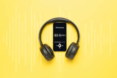 Podcast ikonu. Mikrofonlu ses ekipmanları, ses kulaklıkları, cep telefonu ekranında podcast uygulaması. Sarı arkaplandaki radyo kayıt sesi. Medya müzik konseptini yayınla