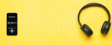 Podcast ikonu. Mikrofonlu ses ekipmanları, ses kulaklıkları, cep telefonu ekranında podcast uygulaması. Sarı arkaplandaki radyo kayıt sesi. Medya müzik konseptini yayınla