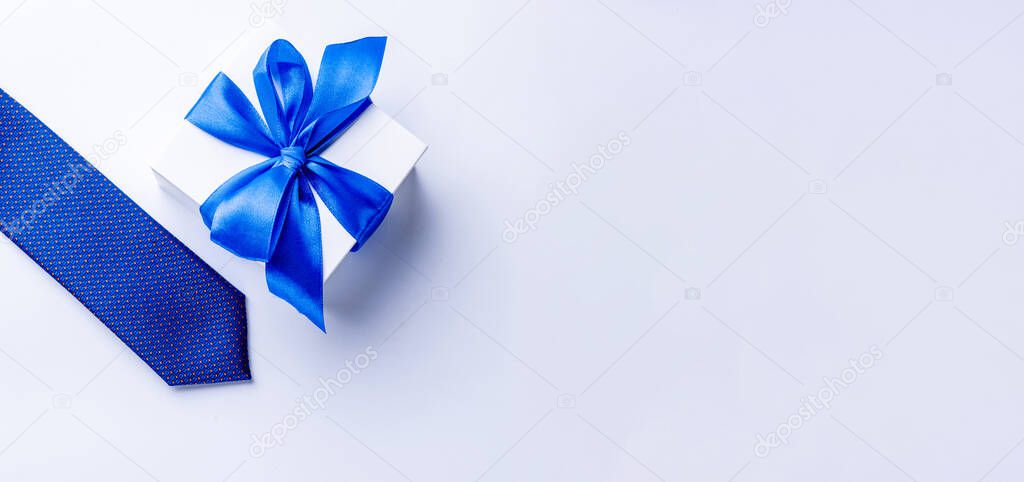 Gift dad. Blue bowtie or tie, white box with bow ribbon on light background. Happy loving family and Fathers Day concept