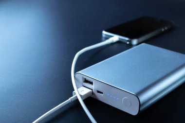 Telefon güç bankası. Cep telefonu ya da akıllı telefon bataryası beyaz USB kabloyla taşınabilir güç bankasından şarj oluyor. Mobil aygıtlar için dış pil
