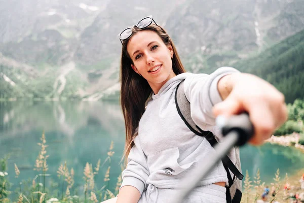 ブロガーの女の子 夏の山の岩の自然を背景にスマートフォンで若い女性旅行写真家 夏の旅行 職業概念 — ストック写真