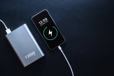 Güç bankasını şarj ediyorum. Şarj cep telefonu ya da akıllı telefon bataryası için beyaz USB kablosu olan taşınabilir güç bankası. Üst görünümde modern teknoloji kavramı