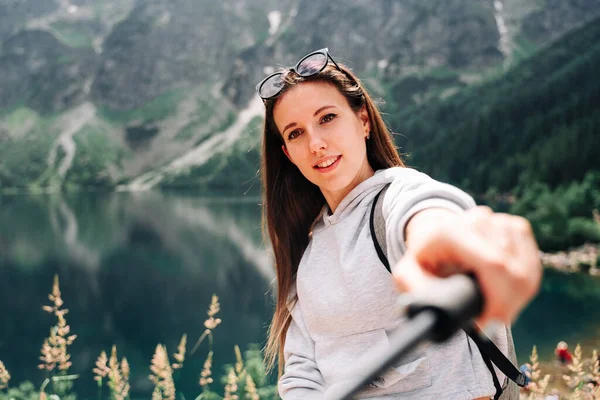 ブロガーの女の子 夏の山の岩の自然を背景にスマートフォンで若い女性旅行写真家 夏の旅行 職業概念 — ストック写真