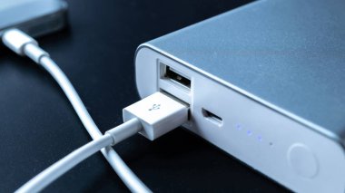 Telefon güç bankası. Cep telefonu ya da akıllı telefon bataryası beyaz USB kabloyla taşınabilir güç bankasından şarj oluyor. Mobil aygıtlar için dış pil
