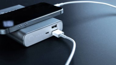Telefon güç bankası. Cep telefonu ya da akıllı telefon bataryası beyaz USB kabloyla taşınabilir güç bankasından şarj oluyor. Mobil aygıtlar için dış pil
